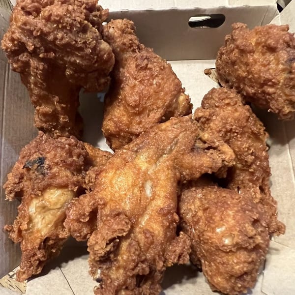 Crispy, golden-brown fried chicken pieces in a cardboard takeout box from The Grotto Restaurant.